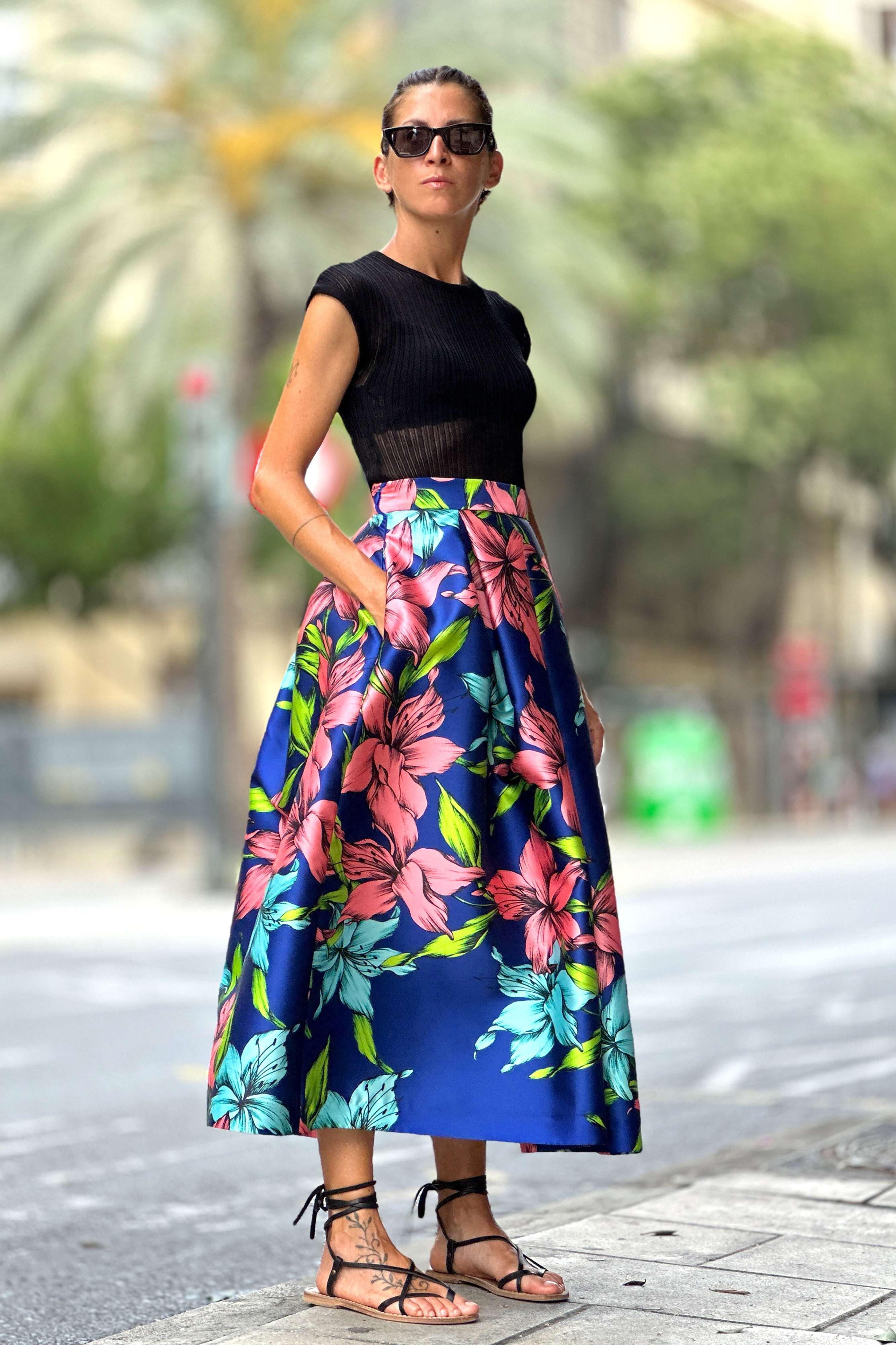 Woman wearing Gonna Big Flower midi skirt with blue floral print and black top outdoors