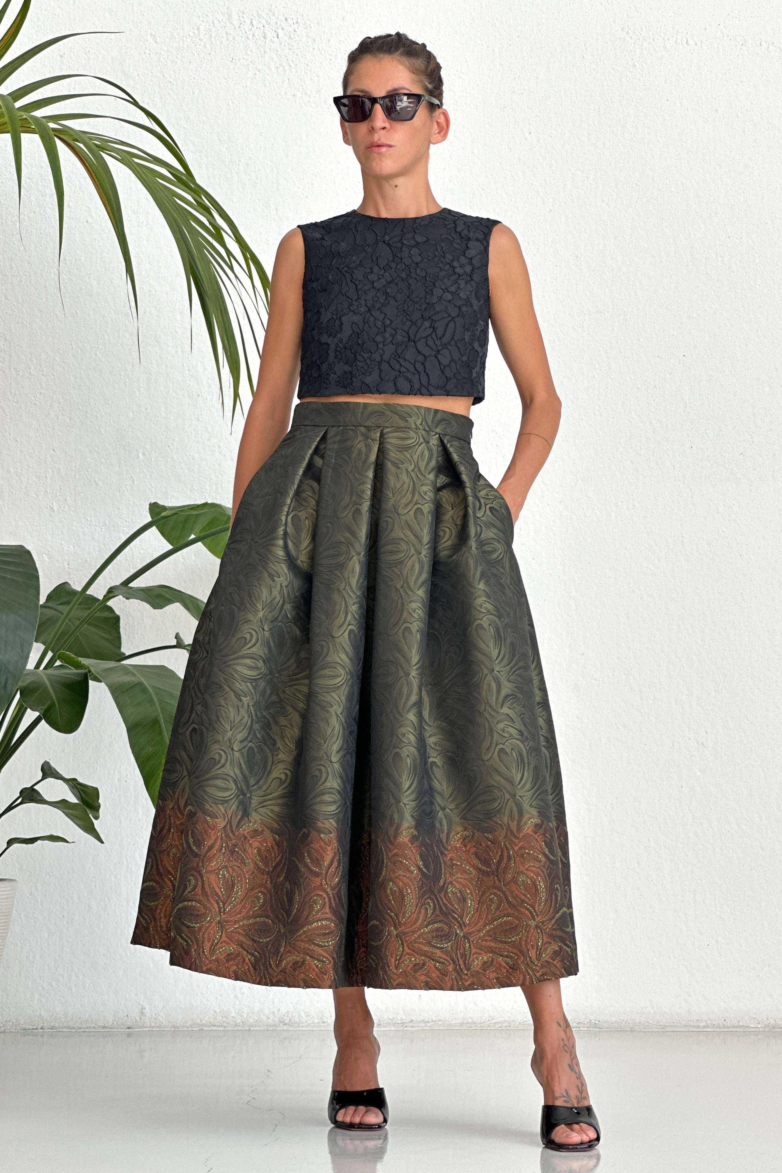 Woman wearing Gonna Bologna Green high-waisted pleated jacquard skirt with distinctive border and pockets