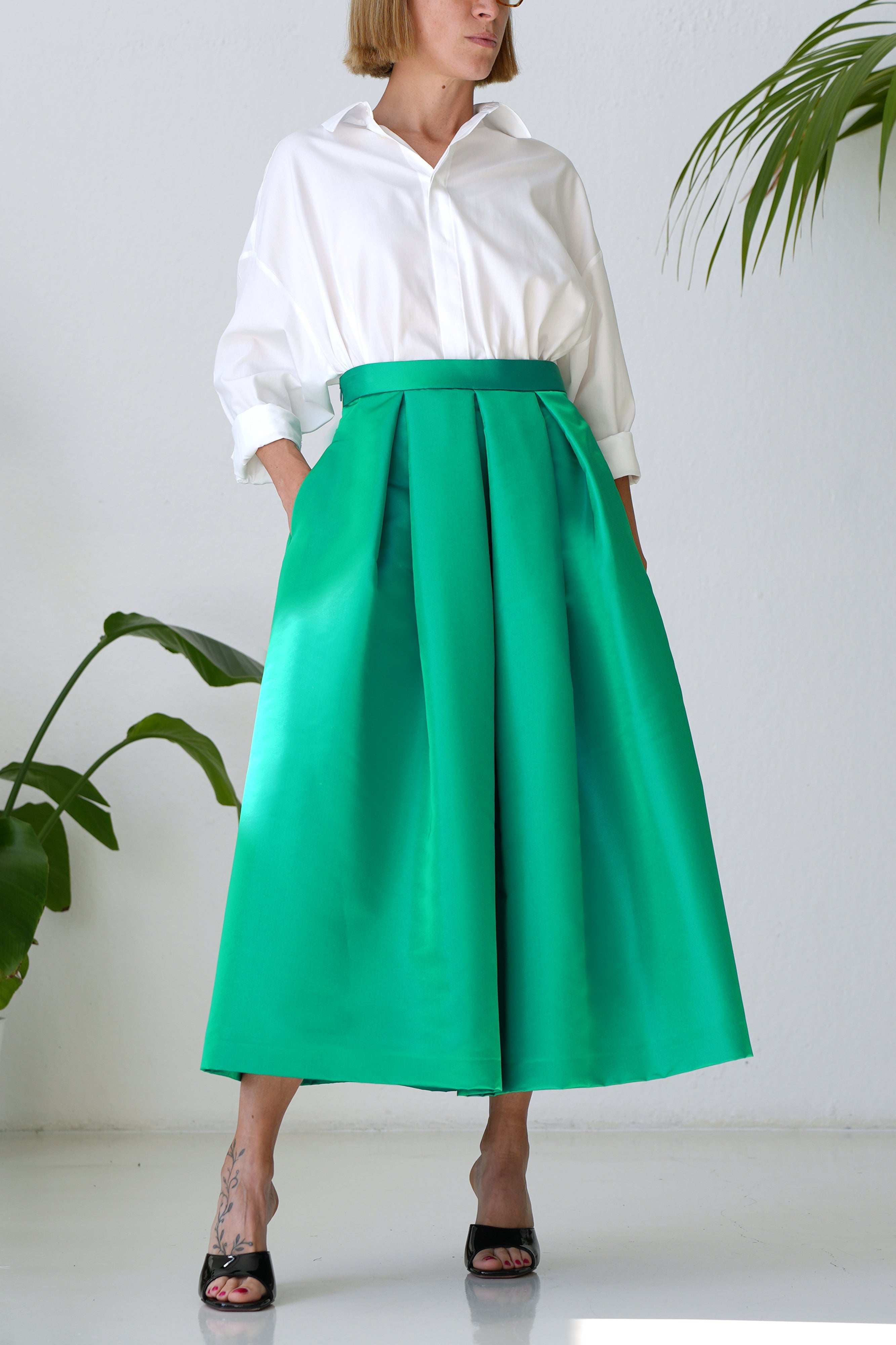 Woman wearing emerald green duchesse pleated skirt with side pockets and invisible zip closure