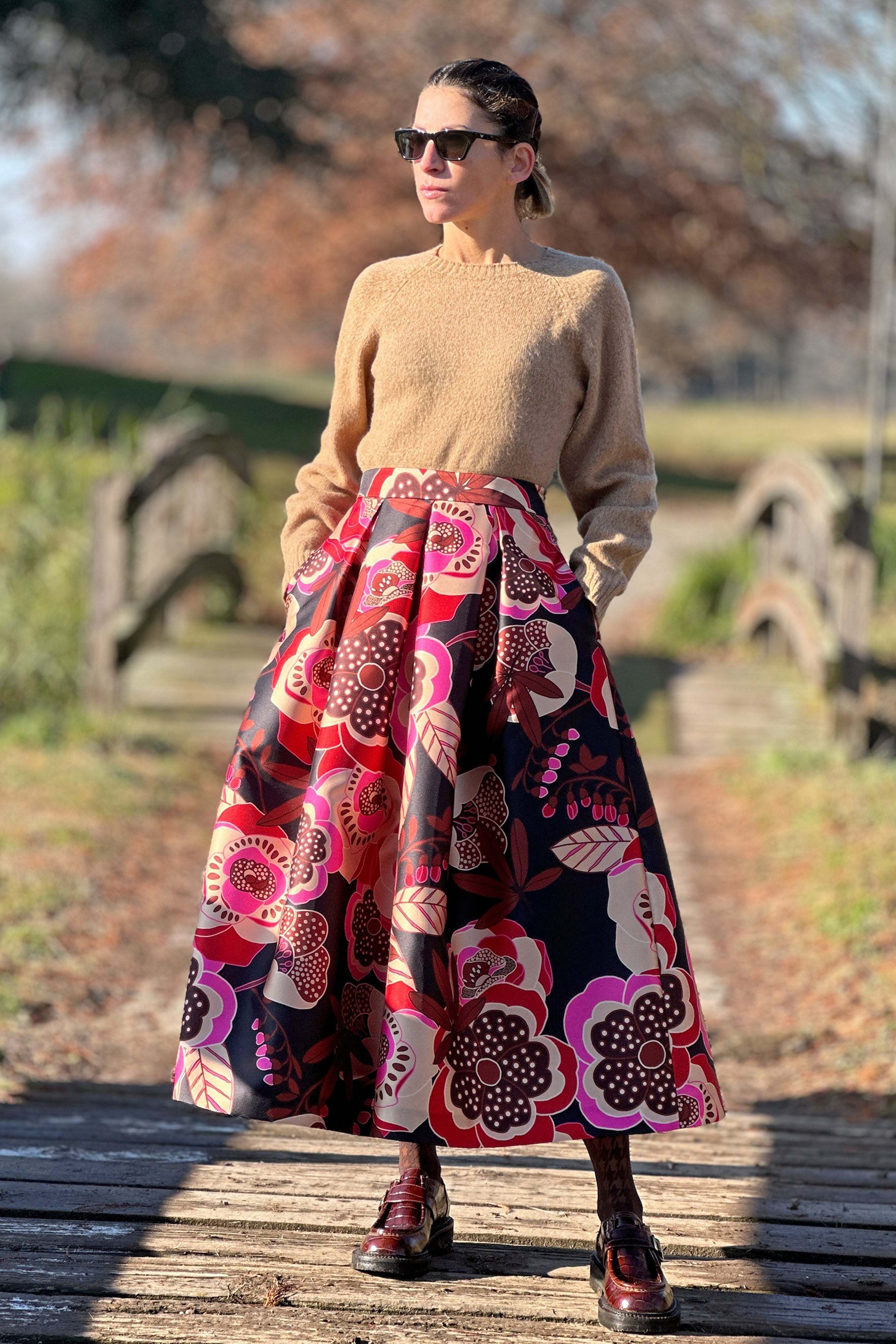 Woman wearing Gonna Garden Black midi skirt with floral print and high waist outdoors