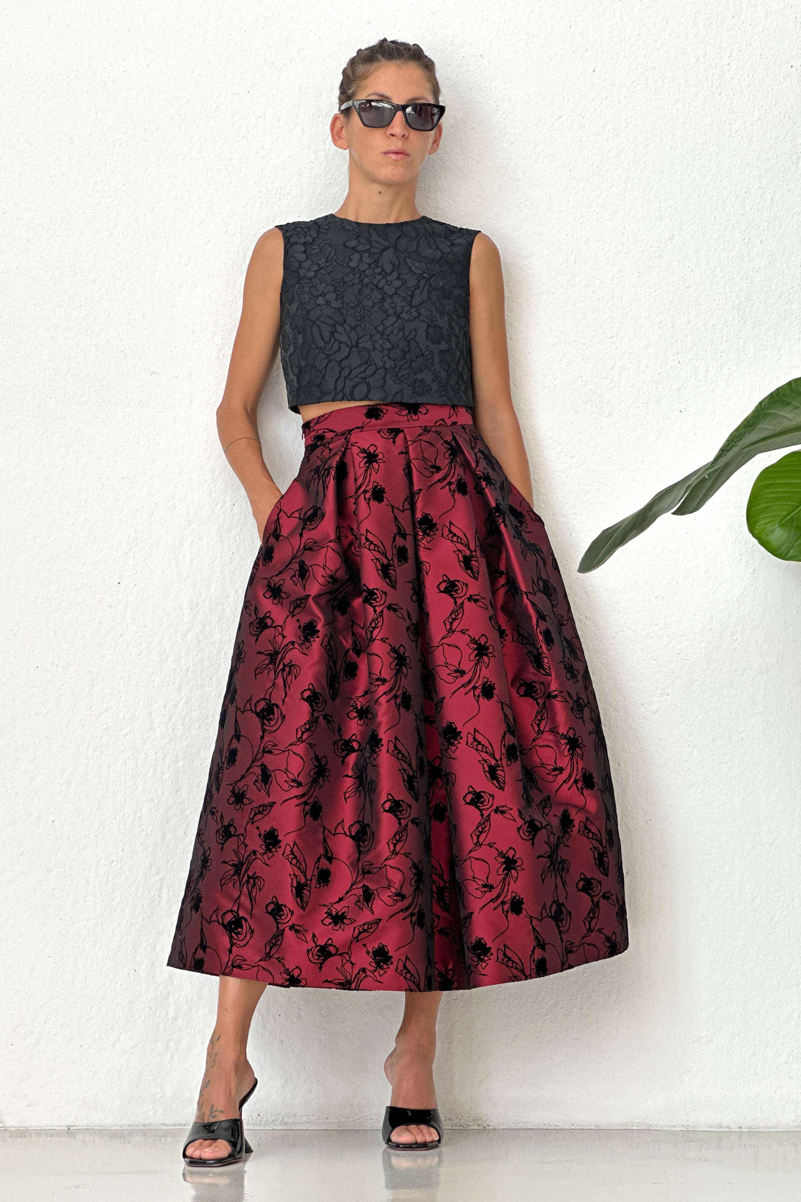 woman wearing red pleated midi skirt with black floral pattern and black sleeveless top