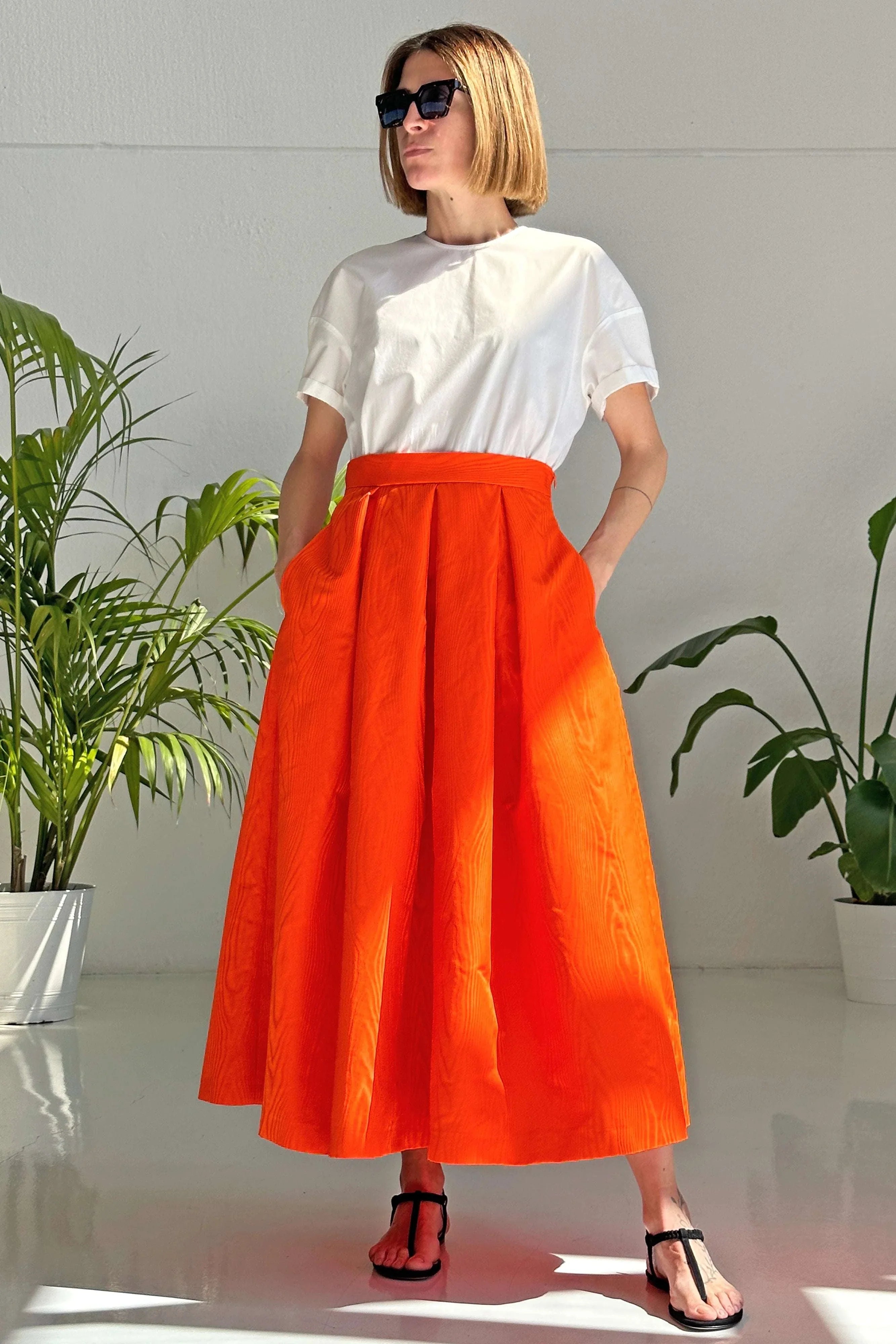 Woman wearing orange midi Gonna Moiré skirt with pockets and high waist paired with white top and sandals