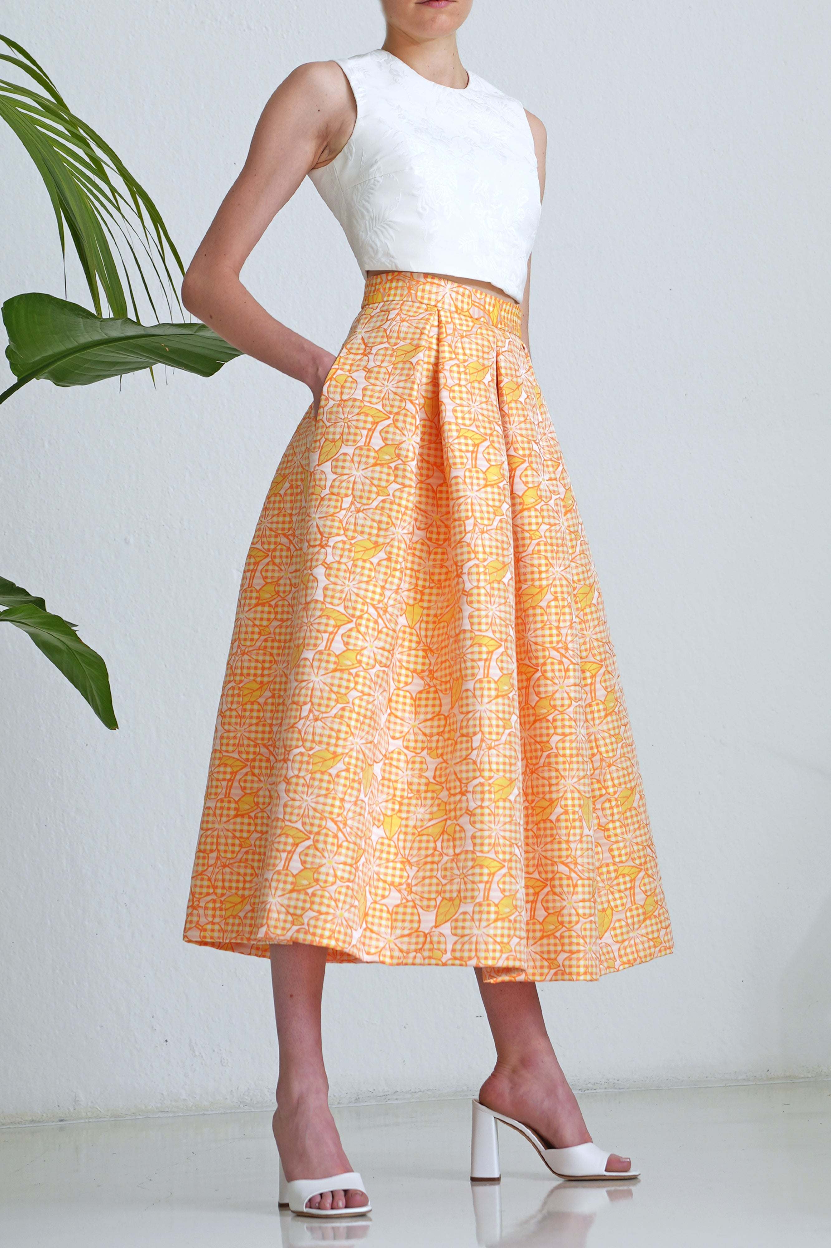 Woman wearing midi length yellow Vichy floral jacquard skirt with high waist and pockets