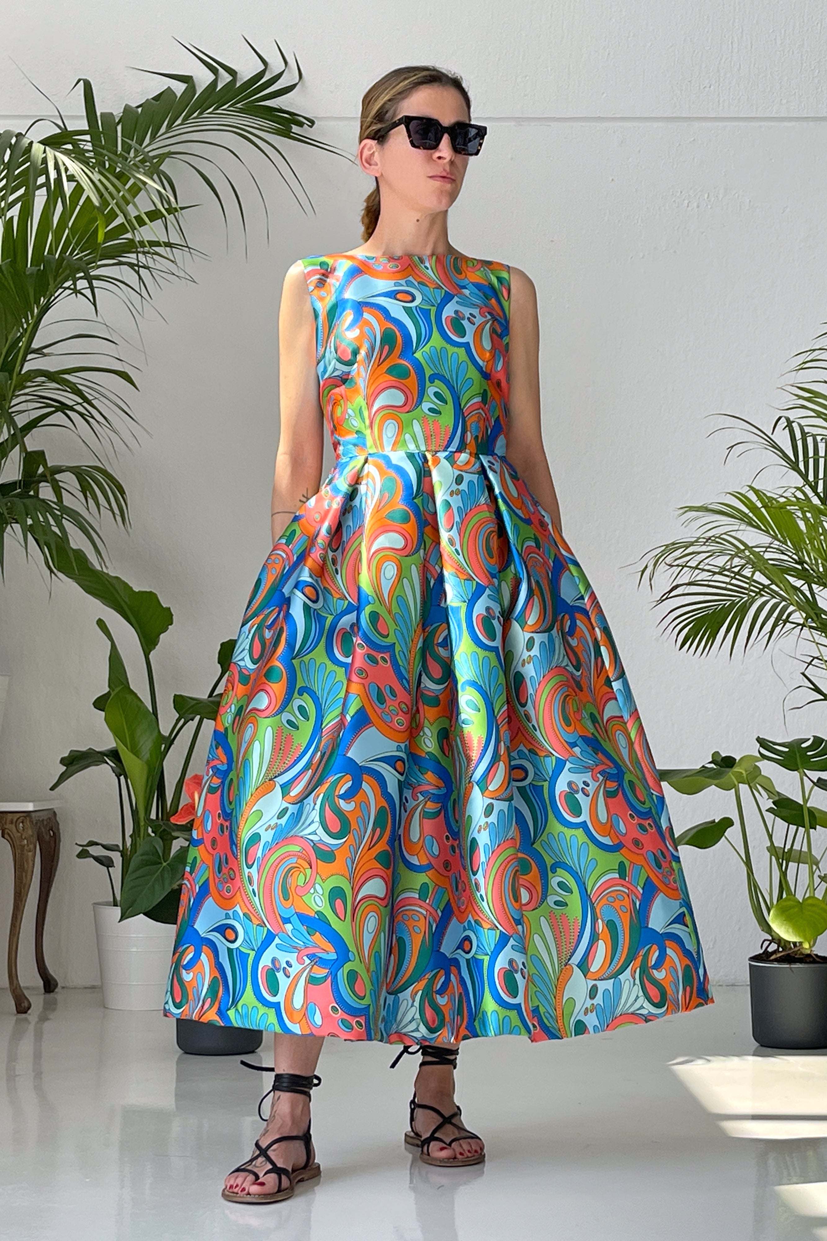 Woman wearing Abito Groovy Blu sleeveless pleated skirt dress with colorful mikado print and V-back neckline