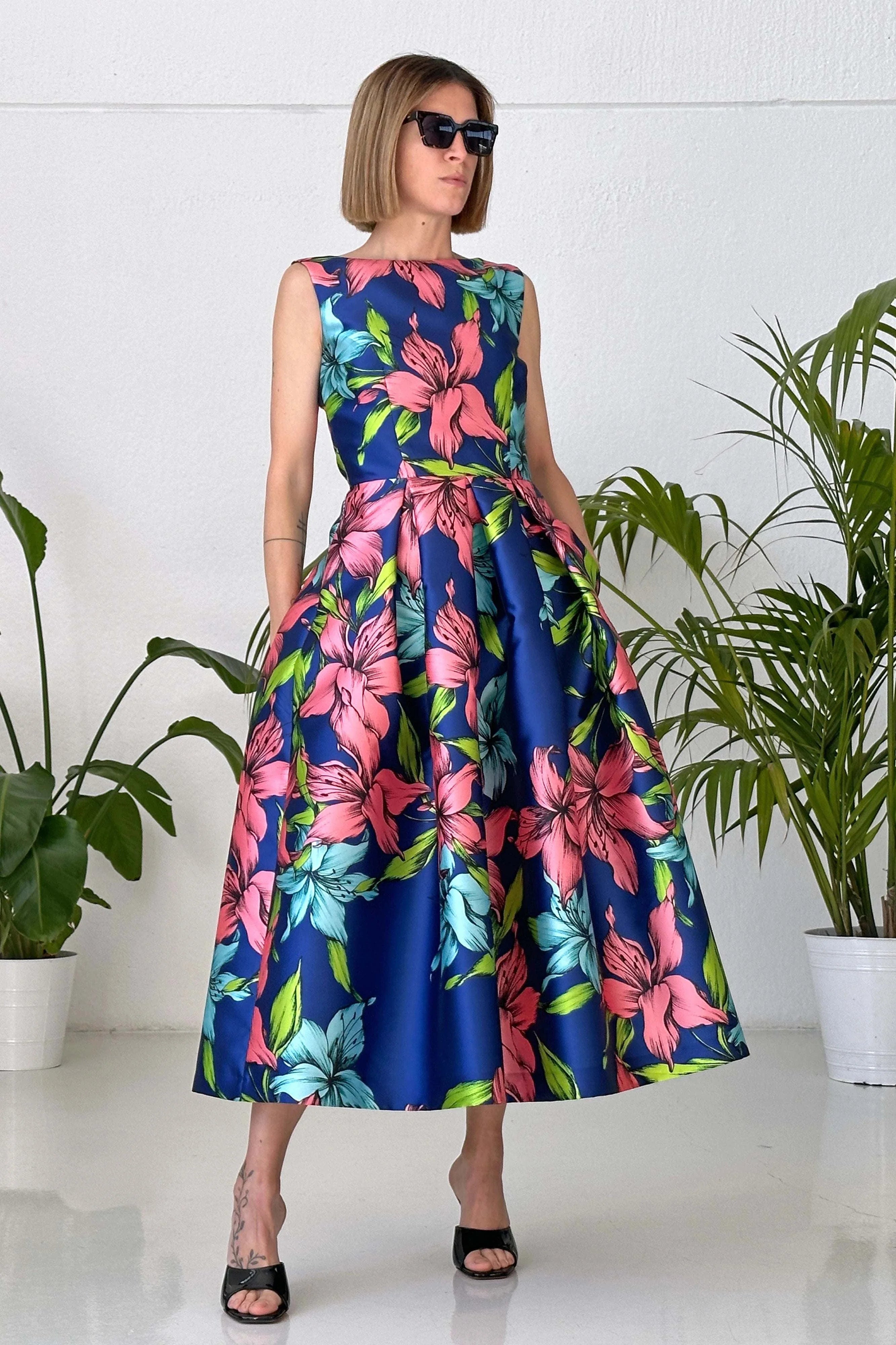 Woman wearing Abito Big Flower sleeveless blue floral V-neck back pleated skirt dress with pockets
