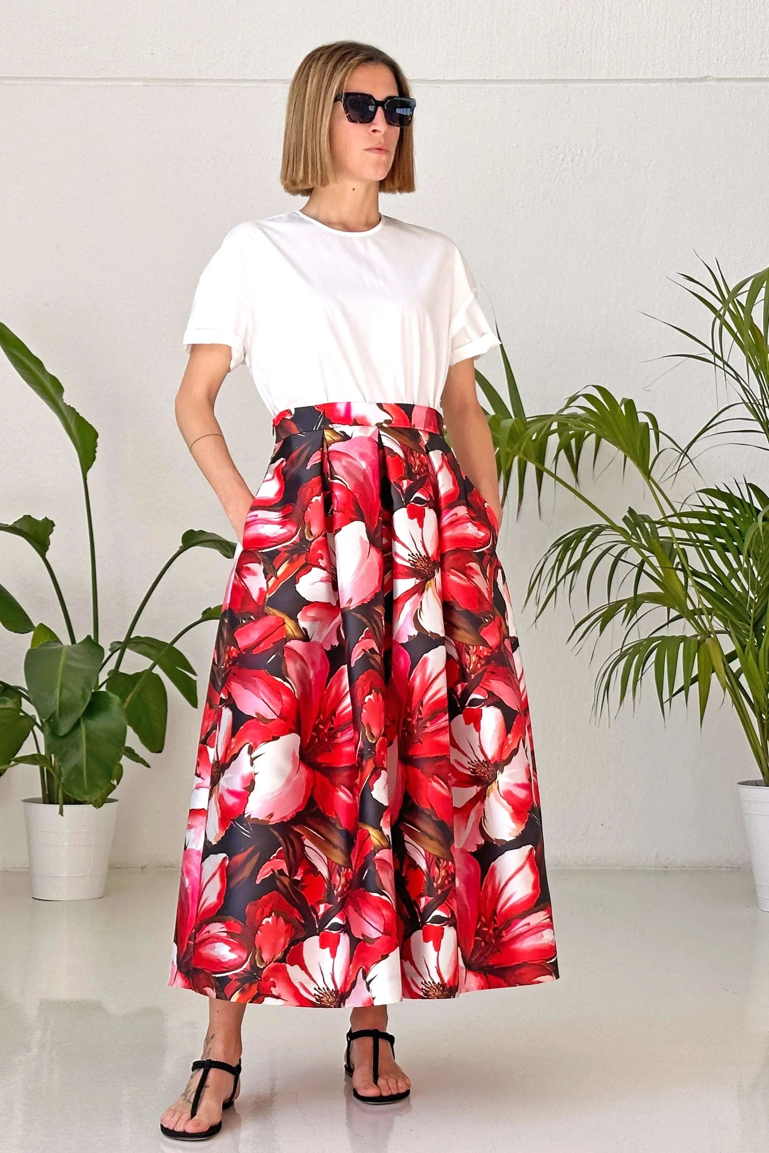 Woman wearing Gonna Floral Red midi skirt with high waist and vibrant red floral pattern with white top and sunglasses indoors.