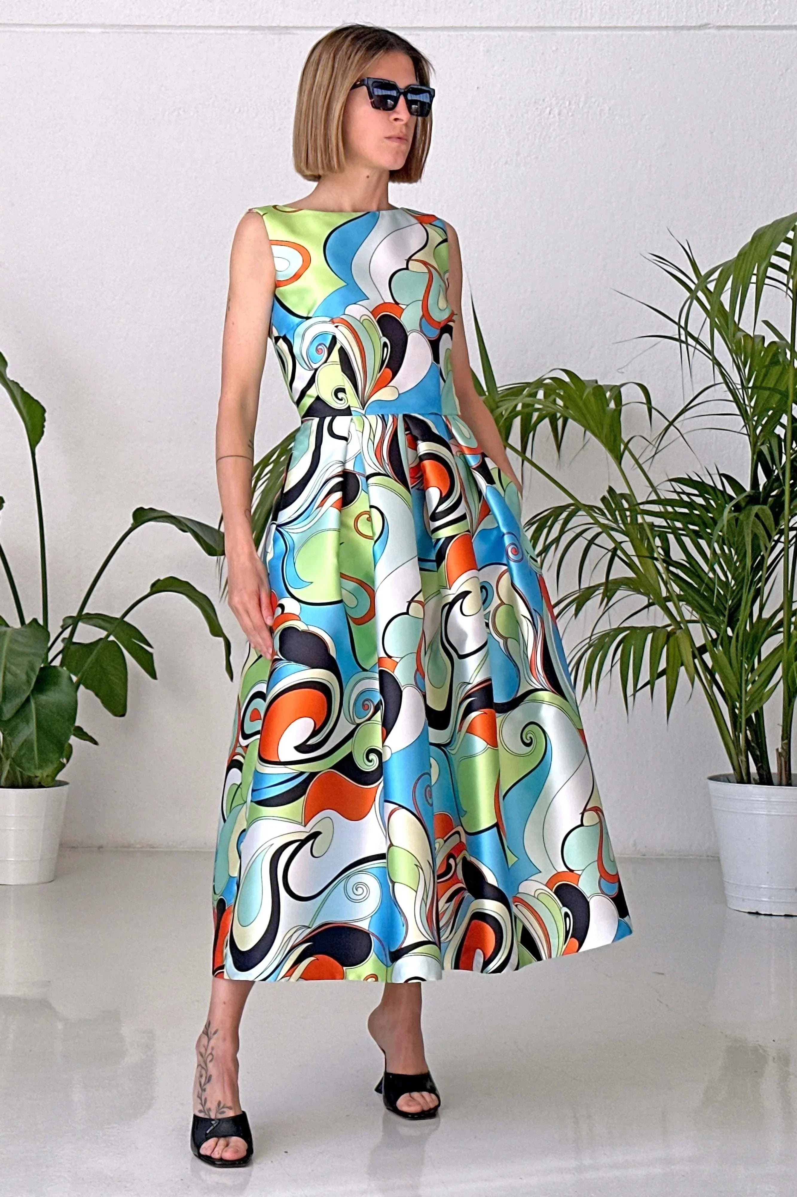 Woman wearing Abito Groovy sleeveless V-neck pleated skirt mikado dress with colorful abstract pattern and pockets