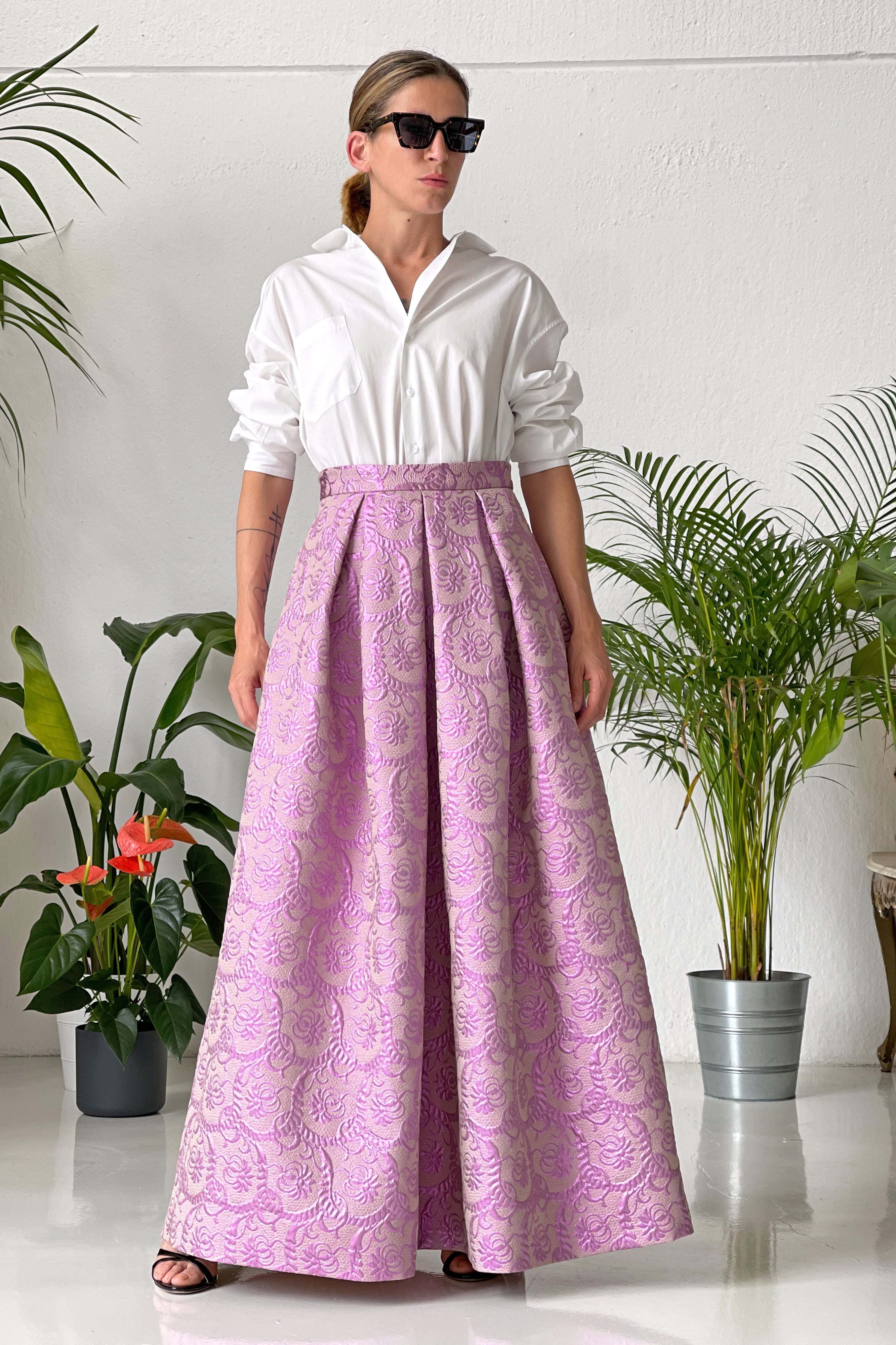 Woman wearing long wide high-waist purple lurex jacquard skirt with white shirt and sunglasses indoors
