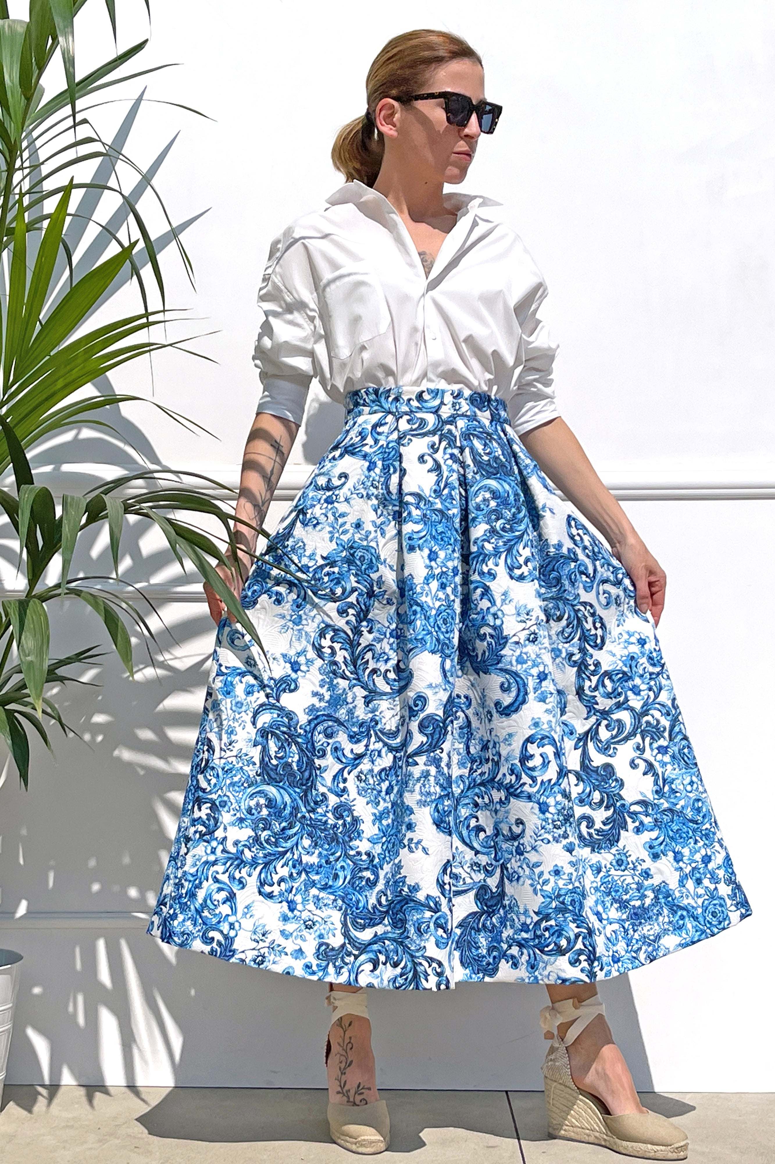 Woman wearing white blouse and blue patterned gonna midi Celestina matelassé skirt with sunglasses and wedge sandals